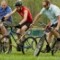 Bike Polo participants chase the ball down the field towards the goal. Bike Polo participants chase the ball down the field towards the goal.